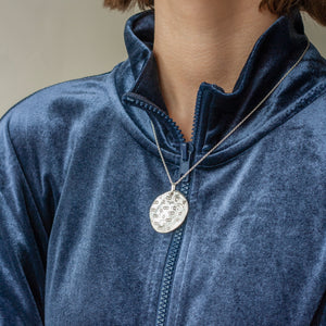 PARAGON II ROUND SILVER PENDANT WITH SQUARE PATTERN ON CHAIN BY MARGO ORLOVIK ON MODEL