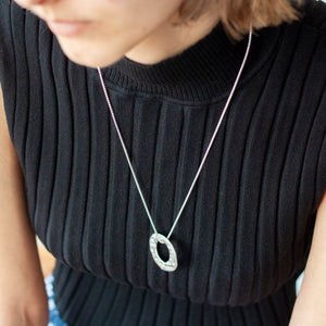 PARAGON VI ROUND SILVER PENDANT ON CHAIN BY MARGO ORLOVIK ON A MODEL 